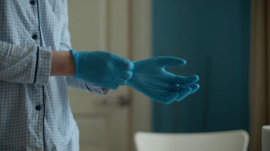 Parlak odada koruyucu eldiven takan genç bir kadının ellerini kapat. Coronavirüs salgını. Sağlık ve güvenlik kavramı. COVID-19 salgını