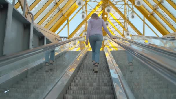 Молодая женщина поднимается по эскалатору — стоковое видео
