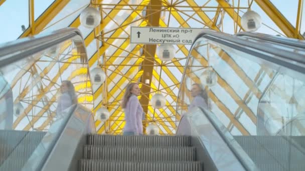 Ung kvinna står på rulltrappan — Stockvideo