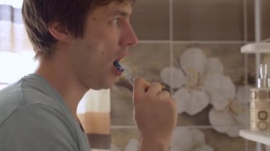 Genç adam dişlerini fırçalıyor.