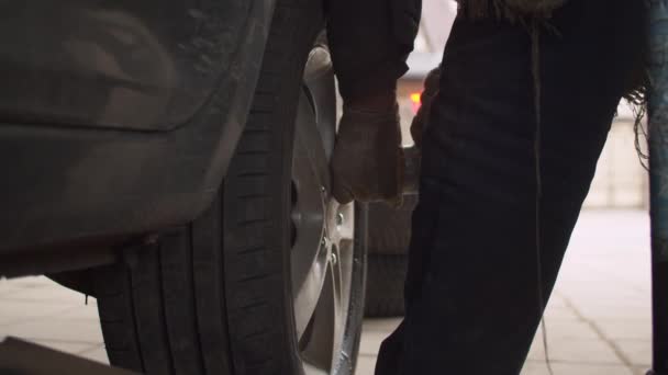 車のサービスで車の車輪の交換 車のホイールに大きなボルトをねじる自動レンチを使用して労働者の手を閉じる — ストック動画