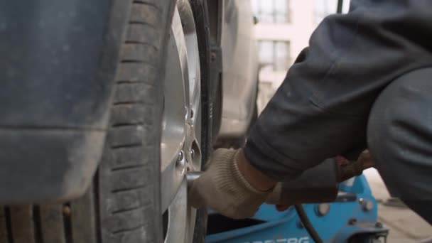 汽车服务中的汽车车轮更换 用气动扳手拧紧汽车车轮上的大螺钉的工人的手 — 图库视频影像