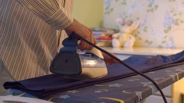 Aydınlık odada erkek el ütüleme pantolonunu kapat. Günlük ev hayatı. Ev erkeği.