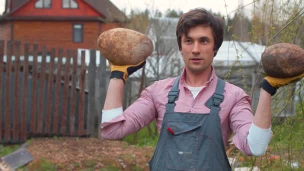 Handsome man carrying two stones in his hands — Stock Video