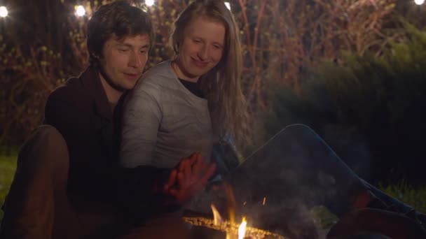 Casal feliz sentado perto de fogueira e abraços — Vídeo de Stock