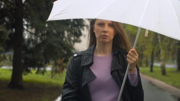 Σοβαρή νεαρή γυναίκα που περπατάει κάτω από ομπρέλα — Αρχείο Βίντεο