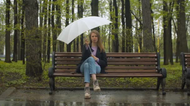 Femme pensive avec parapluie assis sur le banc — Video