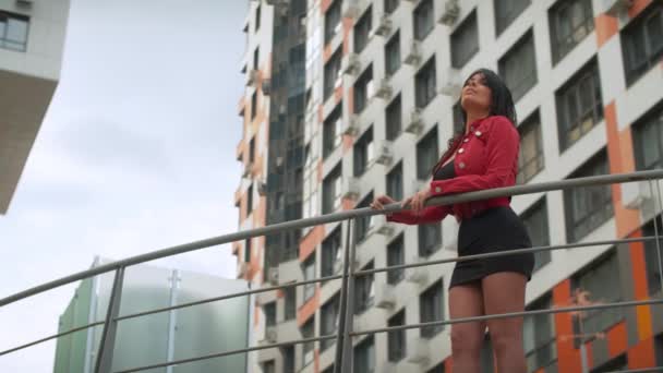 Hermosa mujer en un puente cerca de un edificio moderno — Vídeos de Stock