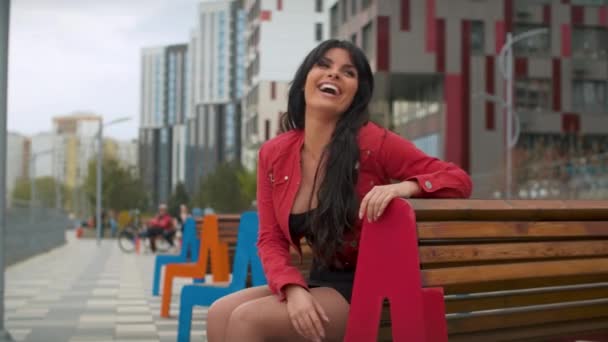 Mujer sonriente sentada en el banco — Vídeo de stock