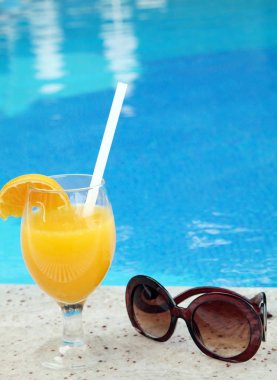 Bardak taze portakal suyu havuz kenarında