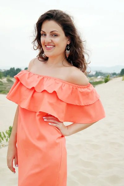 Mujer joven en vestido naranja en la playa — Foto de Stock