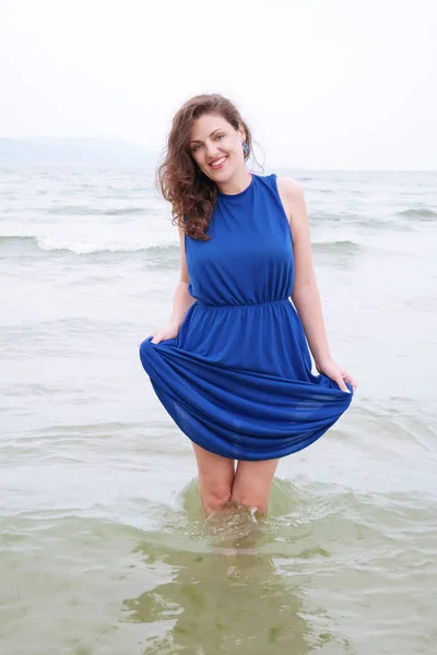 Jonge vrouw in blauwe jurk aan de kust — Stockfoto