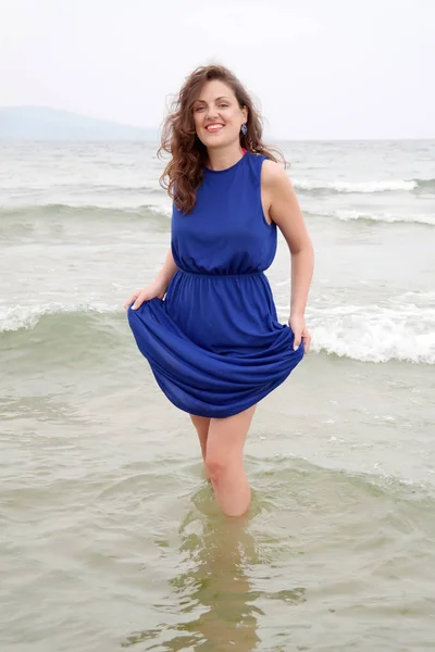 Jeune femme en robe bleue au bord de la mer — Photo