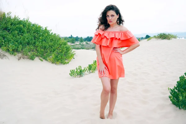 Mujer joven en vestido naranja en la playa Imagen De Stock