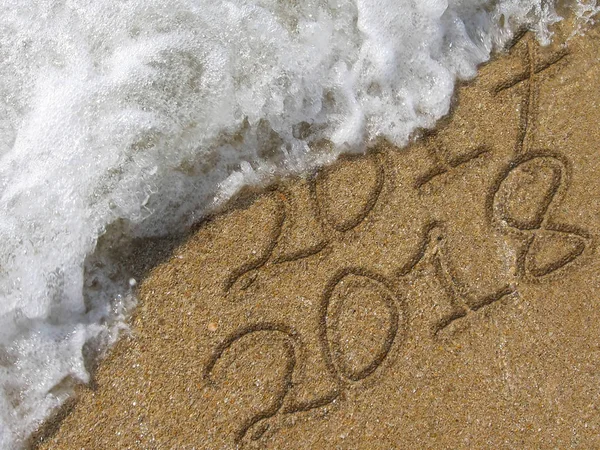 2017 en 2018 geschreven in het natte zand strand — Stockfoto