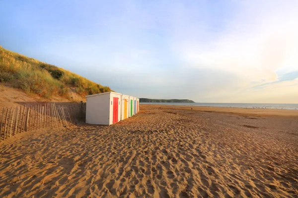 Řada dřevěných malovaných zářivě barevné plážové chatky — Stock fotografie
