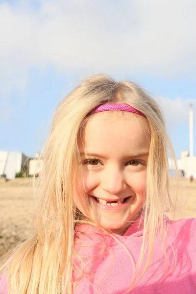 Kis szőke lány a strandon mosolyogva gapis a fogak — Stock Fotó