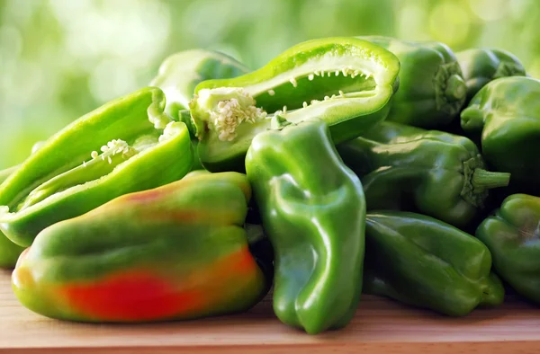 Peppers on table, green background — Stock Photo, Image