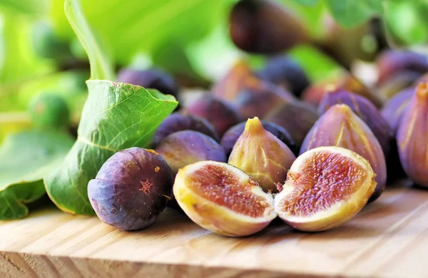 Ripe figs with green leaves on table — Stock fotografie