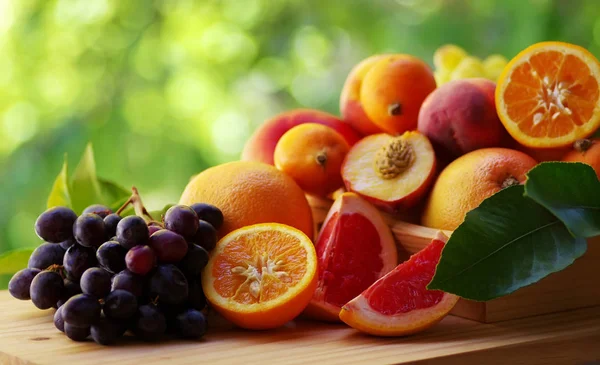 Виноград, нарезанные фрукты и различные фрукты на деревянной корзине — стоковое фото