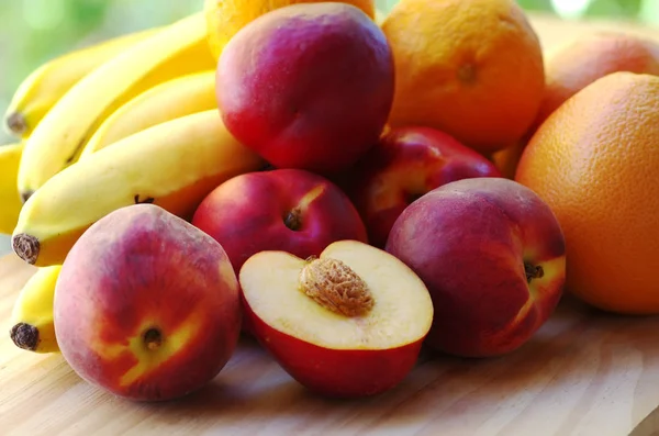 Pêches mûres. bananes et agrumes dans le tableau — Photo