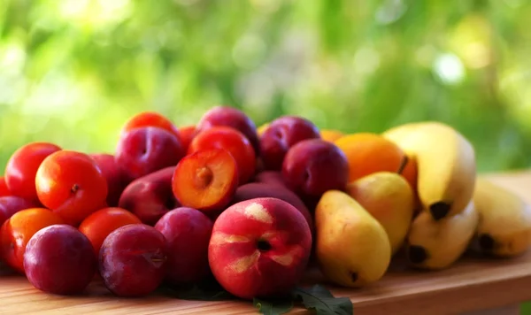 Peach, pear, plums and bananas on table — Stock Photo, Image