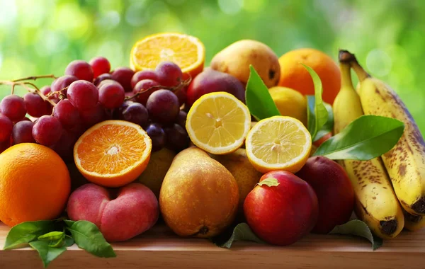 Sortimento de frutas maduras na mesa, fundo verde — Fotografia de Stock