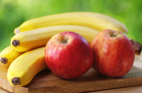 Bananen und Äpfel auf grünem Hintergrund — Stockfoto