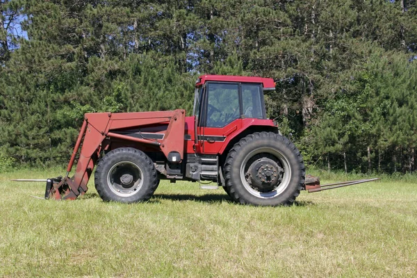 Röda gården traktor på ett grönt gräs betesmark — Stockfoto