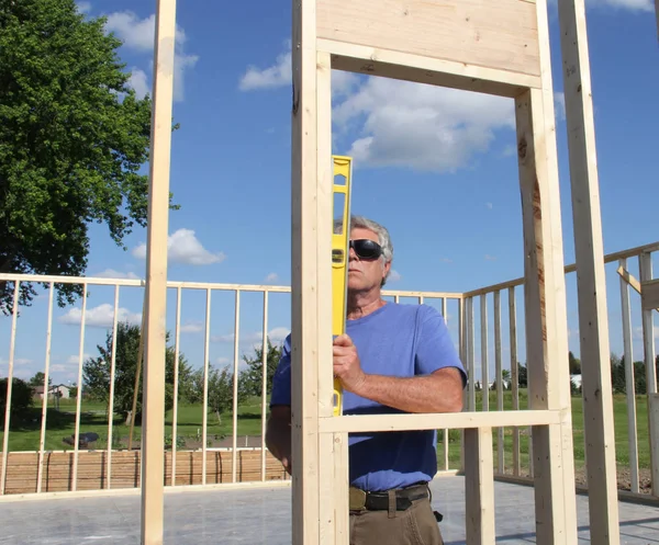 Carpenter reading  a level on a house frame — Stock Photo, Image