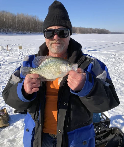 Pescatore che tiene un Crappie mentre pesca sul ghiaccio — Foto Stock
