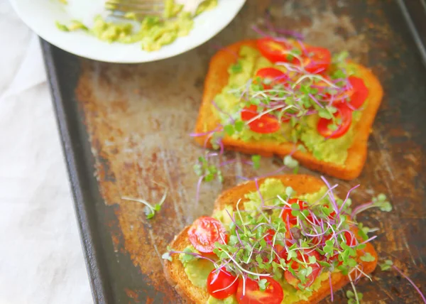 Friske spirer på avocado toast - Stock-foto