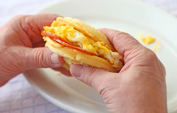 Muž, který držel sendvič se šunkou, vejcem a vafle — Stock fotografie