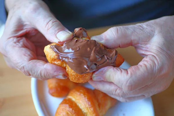 Mannen har croissant spredd med sjokolade – stockfoto
