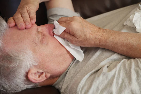 Senior legt sich mit Grippesymptomen hin — Stockfoto