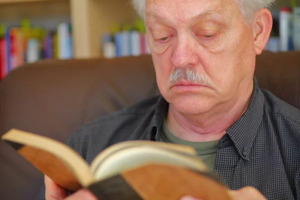 Homem sênior lendo com fundo de estante — Fotografia de Stock
