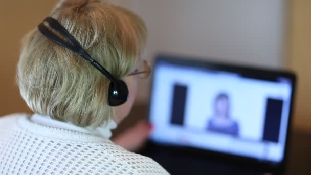 Mujer mayor con auriculares y portátil — Vídeo de stock