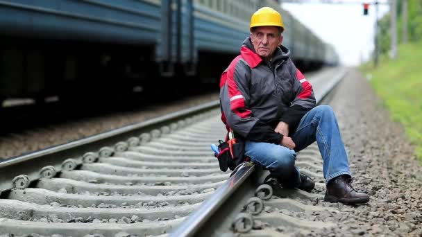 Trabajador se sienta en la línea ferroviaria — Vídeo de stock