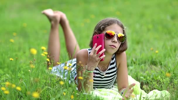 Fille avec smartphone se trouve sur l'herbe — Video