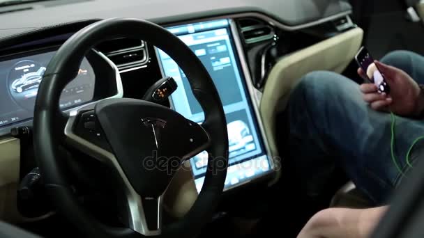 Człowiek z smartphone wewnątrz Tesla electromobile — Wideo stockowe