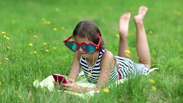 Dívka s červenými smartphone leží na trávě