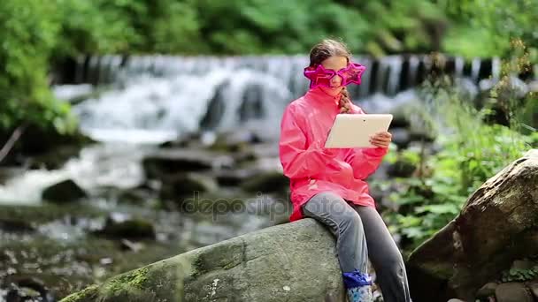 Chica con tableta PC se sienta cerca del río — Vídeo de stock