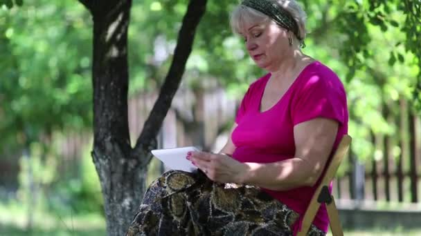 Mujer mayor utiliza un comprimido blanco — Vídeos de Stock