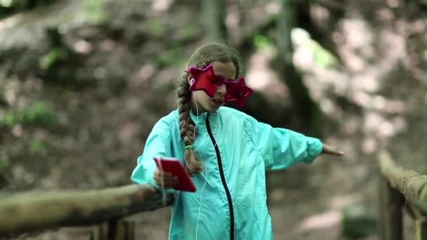 Fille avec smartphone se tient sur le pont en bois — Video