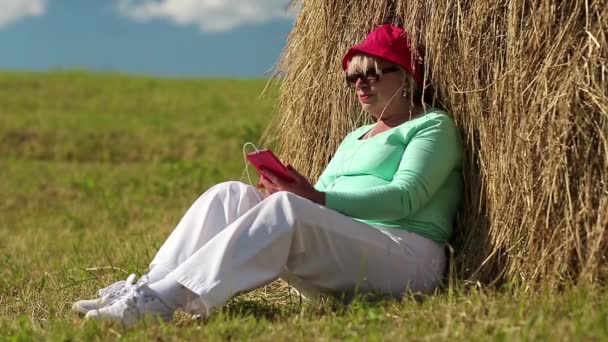 女人红智能手机在草堆里附近 — 图库视频影像