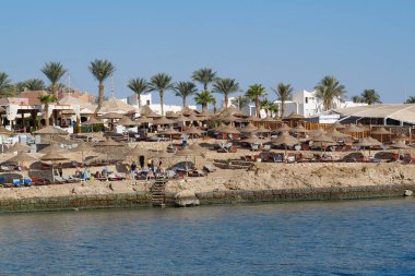 EGYPT, SHARM EL SHEIKH, SINAI, RED SEA, DECEMBER 7, 2019: People on the beach near coast of Red Sea in Sharm El Sheikh, Egypt