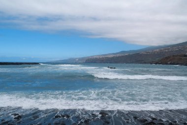 Tenerife Adası, Kanarya Adaları, Atlantik Okyanusu, İspanya 'daki Puerto de la Cruz şehrindeki siyah volkanik kumlarla sahilde dalgalar kopuyor.