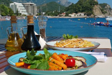 Deniz manzaralı restoranda lezzetli yemekler.