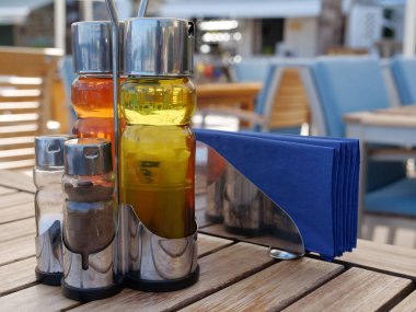 Restaurant table with olive oil, vinegar, salt and pepper, as well as napkins clipart