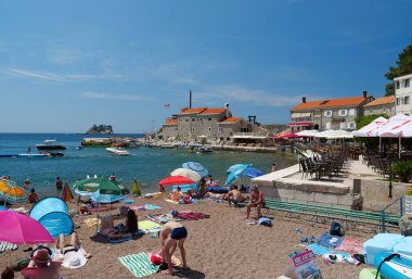 Petrovac, Karadağ, 1 Temmuz 2019: Karadağ 'ın Adriyatik Denizi' ndeki Petrovac kentindeki plajda yaşayan insanlar eski kente bakıyorlar